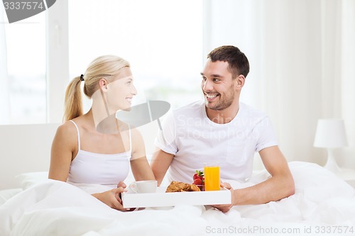 Image of happy couple having breakfast in bed at home