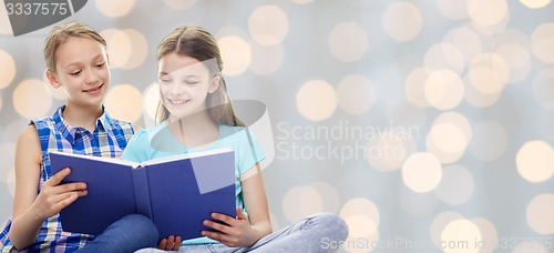Image of happy girls reading book over lights background