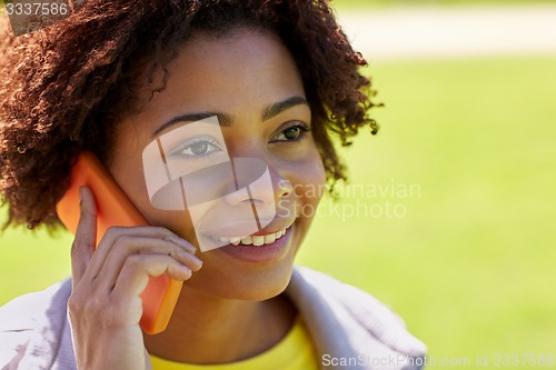 Image of happy african woman calling on smartphone outdoors