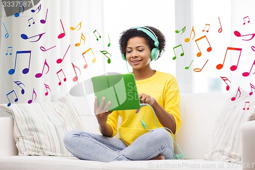 Image of happy african woman with tablet pc and headphones