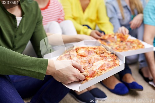 Image of close up of happy friends eating pizza at home