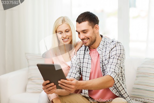 Image of smiling happy couple with tablet pc at home