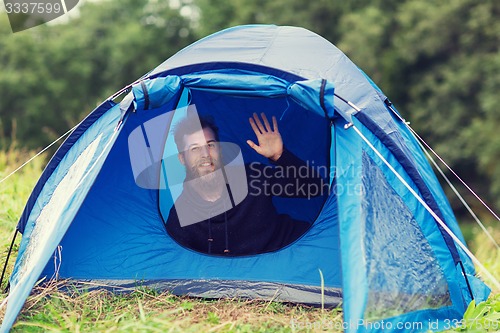 Image of smiling male tourist with beard in tent