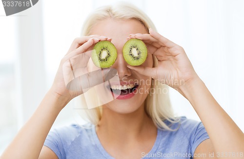 Image of happy woman having fun covering eyes with kiwi