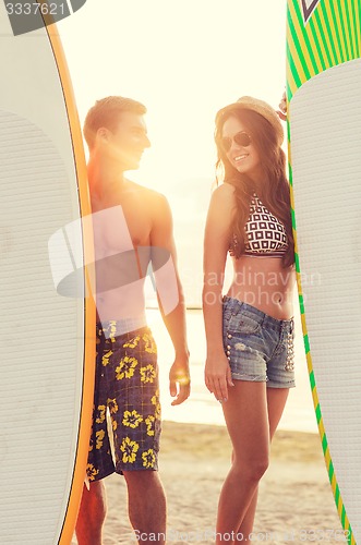 Image of smiling couple in sunglasses with surfs on beach