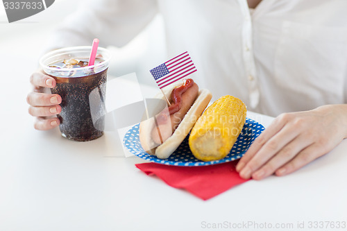 Image of close up of woman eating hot dog with coca cola