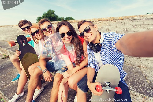 Image of group of smiling friends with smartphone outdoors