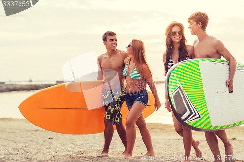 Image of smiling friends in sunglasses with surfs on beach