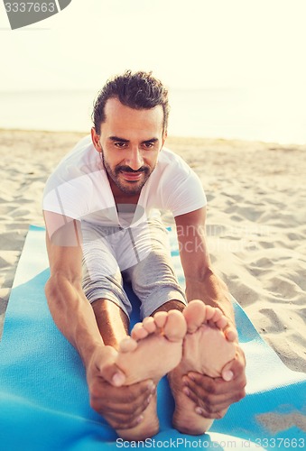 Image of man doing yoga exercises outdoors