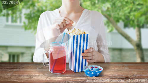 Image of woman eating popcorn with drink in glass mason jar