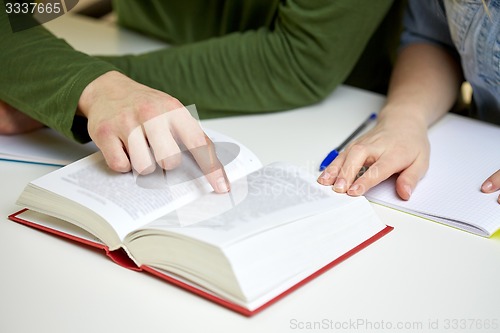 Image of close up of students hands with book or textbook