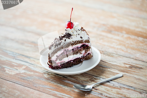 Image of piece of cherry chocolate cake on wooden table