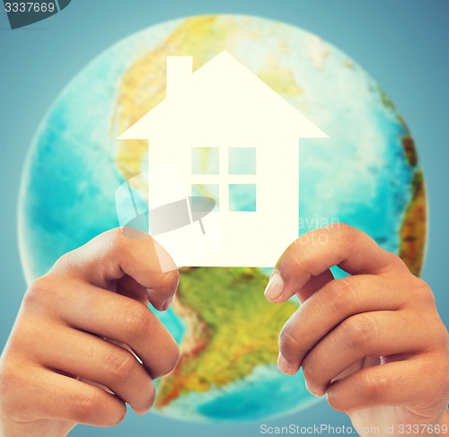 Image of couple hands holding green house over earth globe