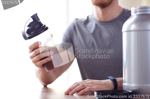 Image of close up of man with protein shake bottle and jar