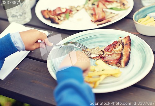 Image of close up of child hands having dinner outdoors