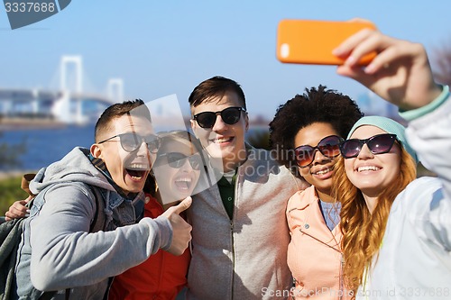 Image of happy friends taking selfie with smartphone