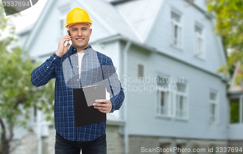 Image of smiling builder in helmet calling on smartphone