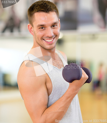 Image of smiling man with dumbbell in gym