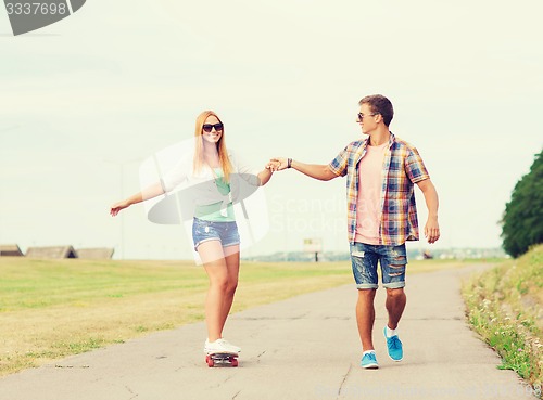 Image of smiling couple with skateboard outdoors