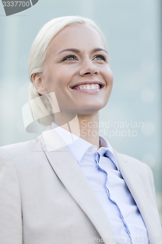 Image of young smiling businesswoman over office building