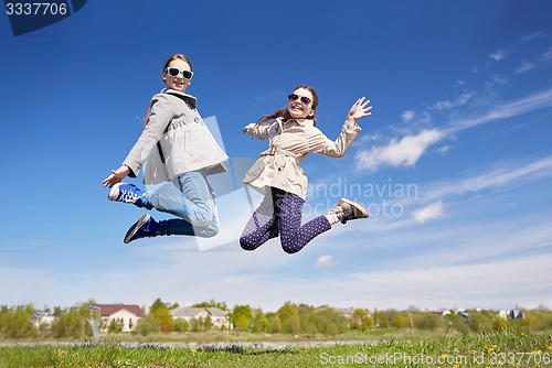 Image of happy little girls jumping high outdoors