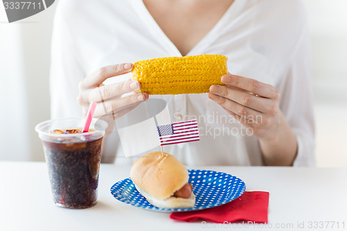 Image of woman hands holding corn with hot dog and cola