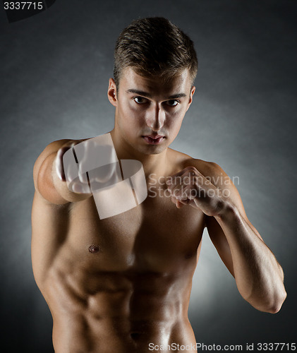 Image of young man on fighting stand over black background