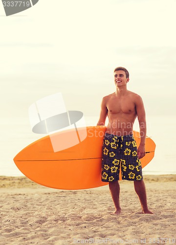 Image of smiling young man with surfboard on beach