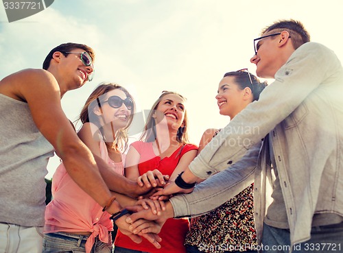Image of group of smiling friends with hands on top in city