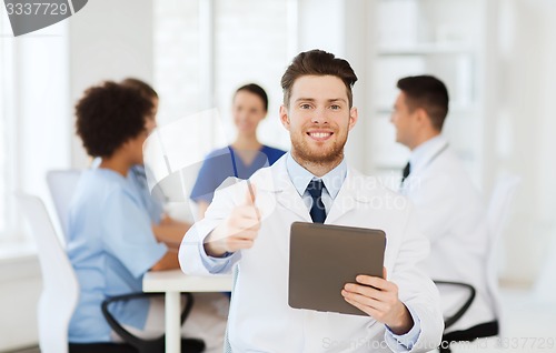 Image of happy doctor with tablet pc over team at clinic