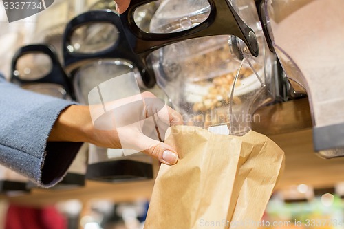 Image of close up of hand pouring nuts to paper bag