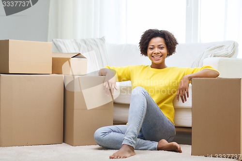 Image of happy african woman with cardboard boxes at home