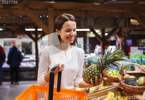 Image of happy young woman with food basket in market