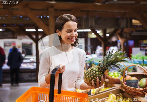 Image of happy young woman with food basket in market