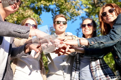 Image of close up of teenage friends with hands on top