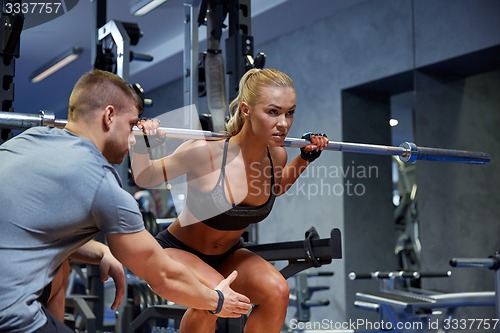 Image of man and woman with bar flexing muscles in gym