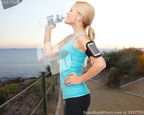 Image of sports woman listening to music and drinking water