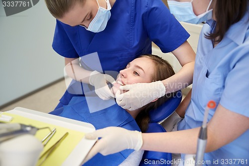 Image of happy female dentist with patient girl at clinic