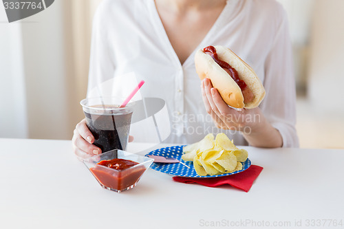 Image of close up of woman eating hot dog with coca cola