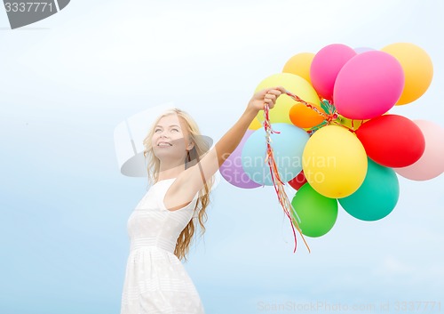 Image of smiling woman with colorful balloons outside