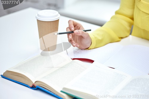 Image of close up of female hands with books and coffee