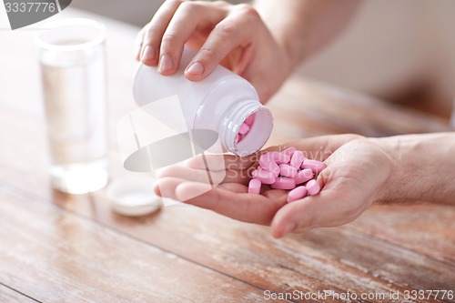 Image of close up of man pouring pills from jar to hand