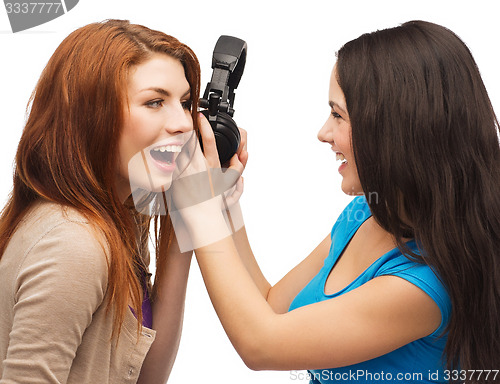 Image of two laughing teenagers sharing headphones
