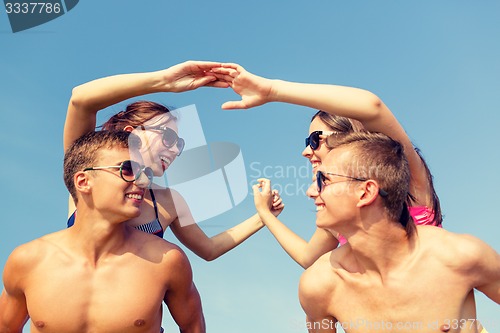 Image of smiling friends in sunglasses on summer beach