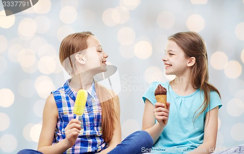 Image of happy little girls eating ice-cream over lights