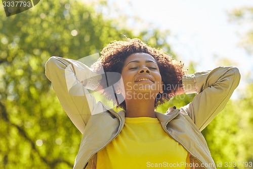 Image of happy african american young woman in summer park