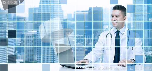 Image of smiling male doctor with laptop sitting at table