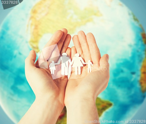 Image of human hands holding paper family over earth globe