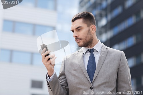 Image of serious businessman with smartphone outdoors