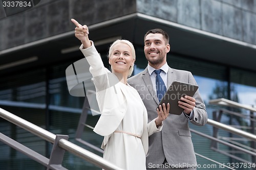 Image of smiling businessmen with tablet pc outdoors